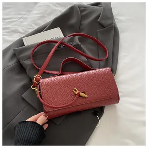 Detail of red woven texture handbag with golden knot buckle on grey suit background