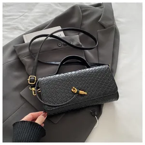 Detail of black woven texture handbag featuring a unique gold twisted metal clasp lock