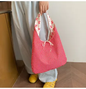 Detail of red gingham canvas tote bag featuring interior bow prints and drawstring bow tie