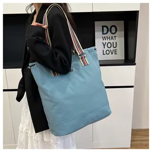 Detail view of blue canvas tote bag featuring adjustable drawstring and striped strap