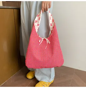 Detail of red gingham tote bag featuring a decorative pink bow and floral inner lining