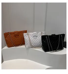 Quilted tote bags in caramel, white, and black with leather chain straps on display