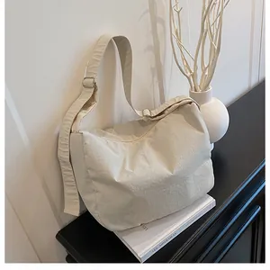 Close-up of the textured cream-colored nylon shoulder bag on a minimalist desk