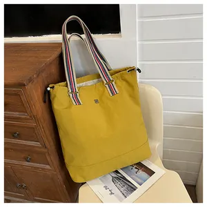 Macro detail of mustard yellow tote bag with colorful striped strap and drawstring top