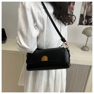 Gros plan d'un sac baguette en cuir noir avec boucle dorée porté à l'épaule