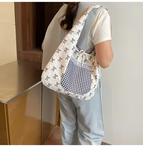 Detail of canvas tote bag featuring blue bow patterns and a lace-trimmed plaid pocket