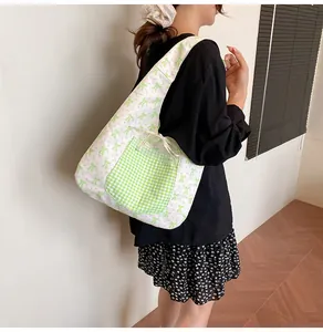 Detail of floral tote bag showing green plaid pocket with lace trim and ribbon ties