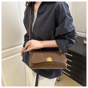 Détail d'un sac à bandoulière en cuir marron brillant avec boucle dorée demi-lune