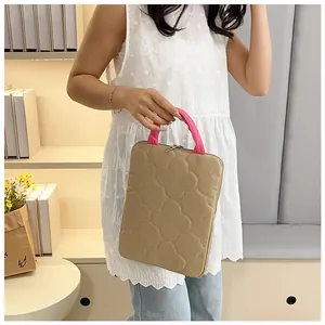 Detalle de la funda acolchada para portátil con asa rosa en un ambiente acogedor