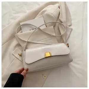 Détail d'un sac à rabat crème avec boucle dorée posé sur un blazer beige élégant