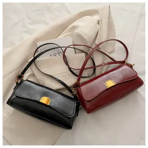 Détail de sacs baguette en cuir noir et bordeaux avec fermoirs dorés sur un blazer