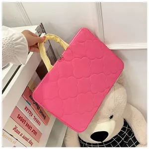 Detalle de funda rosa acolchada para portátil con asa amarilla y diseño de trébol