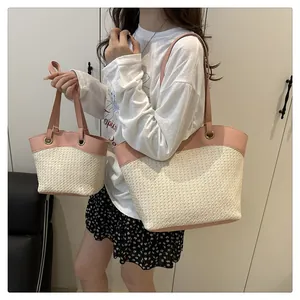Détail d'un ensemble de sacs en paille tressée avec anses en cuir rose en intérieur