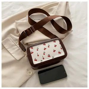 Detalle del bolso bandolera de cerezas con móvil para referencia de tamaño real
