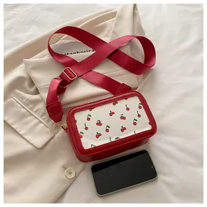 Detalle del bolso bandolera rojo cuadrado con estampado de cerezas y correa ancha