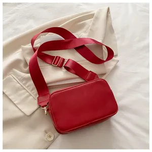 Bolso bandolera rectangular rojo sobre blazer beige con detalles en metal dorado fino
