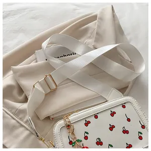 Detalle del bolso bandolera de cuero blanco con estampados de cerezas y cadena dorada