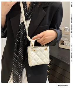 Detail showing white quilted mini bag with glossy finish and gold metal hardware