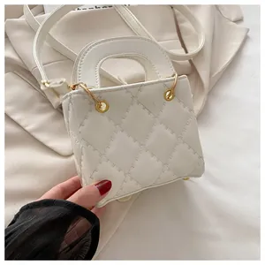 Detailed macro view of white quilted mini handbag with luxury gold round metal handle