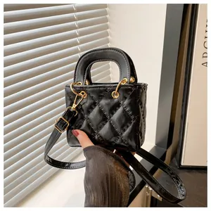Detail of black quilted mini handbag featuring golden rings and elegant shadow play