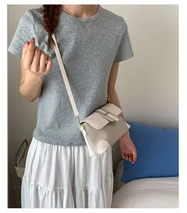 Detail of a beige leather and woven crossbody bag worn by a model in a cozy setting