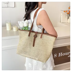Dettaglio della borsa tote in paglia con manici in pelle marrone e trama estiva chic