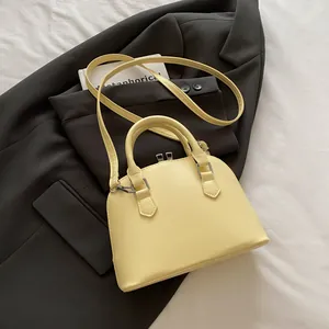 Detail view of a pale yellow shell handbag with smooth PU leather and silver hardware