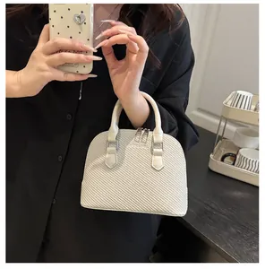 Detailed close-up of cream textured dome handbag with dual zippers and woven pattern
