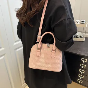 Pink shell tote bag with woven texture and adjustable strap worn by a model