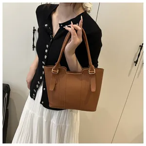 Détail du sac cabas marron en cuir avec motif litchi et boucles métalliques dorées