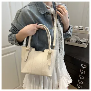 Détail du sac cabas blanc crème à motif litchi, texture cuir et finitions dorées