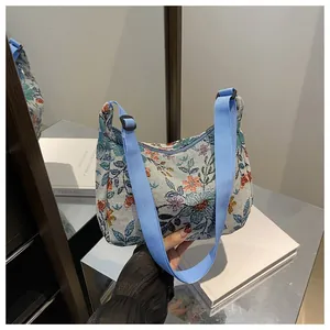 Detail of vintage floral fabric texture and adjustable blue nylon strap on handbag