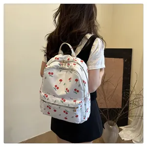 Detail of a white canvas backpack with cherry print worn by a model for a stylish look