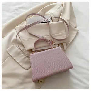 Detailed shot of a pink textured trapezoid handbag on a cream suit and book