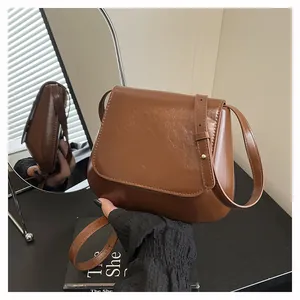 Detail of vintage chestnut saddle bag in shiny brown leather with adjustable strap