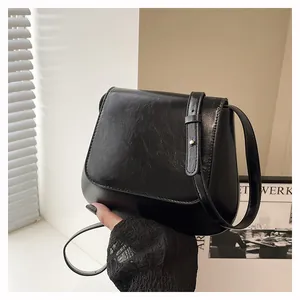 Close-up of black oil-waxed leather saddle bag with smooth curves and adjustable strap