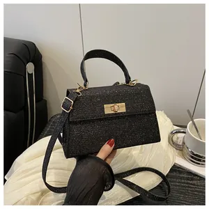 Macro detail of sparkly black glitter handbag featuring a gold metallic twist lock