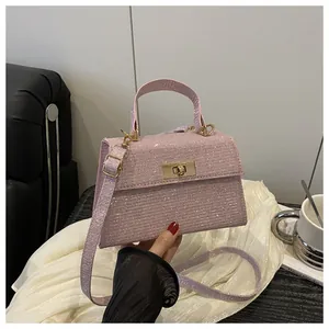 Close-up of pink glitter trapezoid handbag with gold rotating lock and top handle