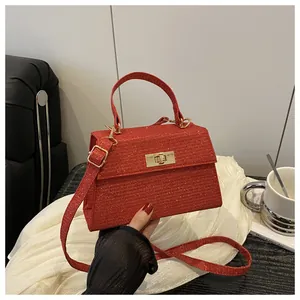 Detail of red glitter crossbody bag with golden rotary lock and sparkling finish