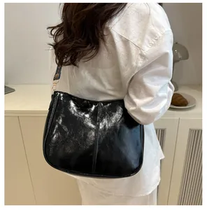 Detail of glossy black hobo bag with vintage stitching and colorful ethnic strap