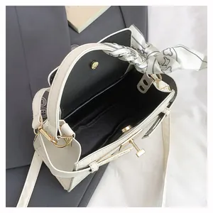 Detail of white crocodile pattern handbag with interior magnetic buckle and silk scarf