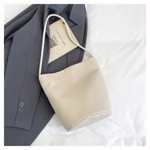 Vue détaillée du cuir grainé beige sur un sac seau au design minimaliste épuré