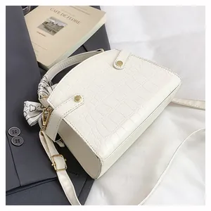 Detail of cream white faux crocodile leather crossbody bag with silk scarf and gold buckles