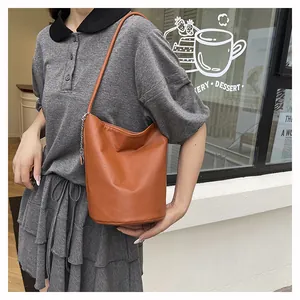 Détail d'un sac seau en cuir marron souple avec une petite chaîne décorative en métal