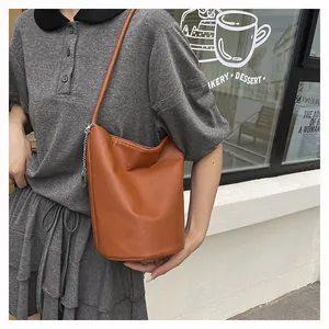 Détail de la texture d'un sac seau en cuir marron avec une chaîne en métal argenté