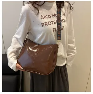 Detail of glossy brown tote bag featuring retro patterned wide strap and gold hardware
