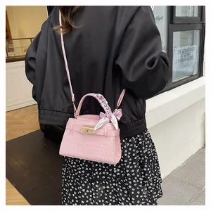 Detail of pink croc-pattern handbag with floral scarf handle worn with black jacket