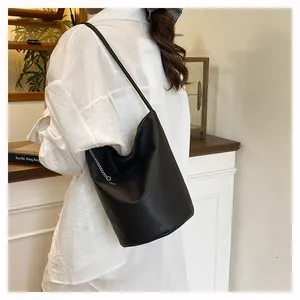 Détail du sac seau en cuir souple noir avec chaîne argentée et texture grainée
