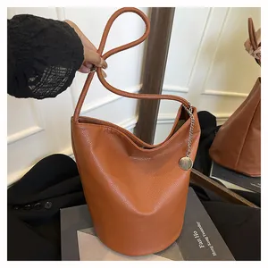 Détail du sac seau en cuir marron caramel souple avec breloque argentée et texture grainée