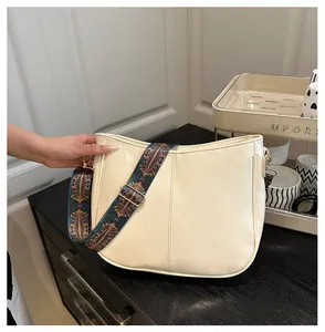 Detail of off-white PU leather hobo bag with bohemian colorful wide strap and gold hardware